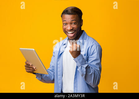 Cheerful African American Guy Holding Tablet Gesturing Yes, Studio Shot Stock Photo