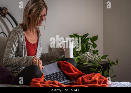 Young woman working from home on her computer.  Working mom. Stock Photo