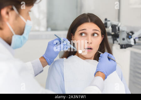 Scared woman looking at dentist before treatment Stock Photo