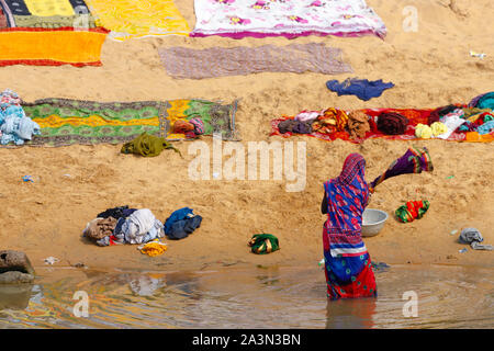 Indian woman washing colorful clothes in the river Stock Photo