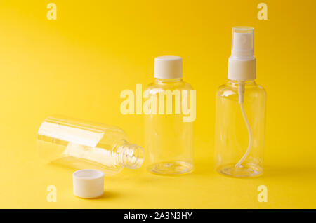 Empty plastic bottles on yellow background. Travel kit for liquid products. Stock Photo