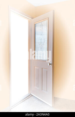 Vertical shot of an open door that leads into the light. Stock Photo