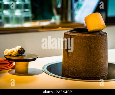 A bamboo ladle rests across the iron kettle (furo), with a folded white cloth and a small black sphere set out on a lacquer tray beside it – utensils of the matcha tea ceremony at the Chaki Chaki café, Yoshina near Izu, Japan. Stock Photo