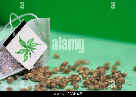 Cannabis tea bag with hemp seeds on green background, hemp tea concept with copy space Stock Photo