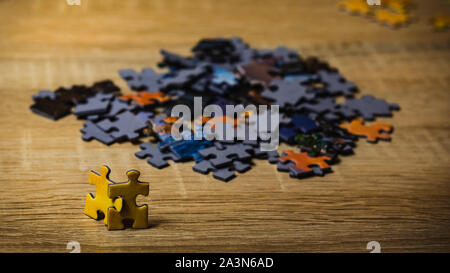 Two yellow puzzles looking at a large group of other puzzles. Concept of attempting to join a group. Stock Photo