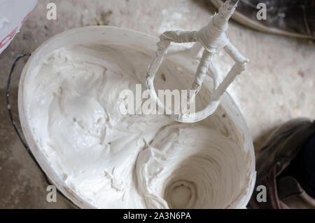 Mixing putty solution in a pail. Construction works concept Stock Photo
