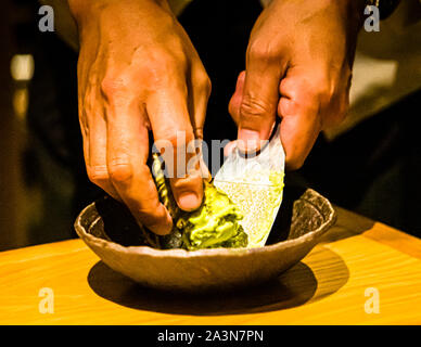 A waiter grates fresh wasabi by hand into a green paste on a traditional sharkskin grater (oroshigane), restaurant in Shizuoka, Shizuoka Prefecture, Japan. Stock Photo