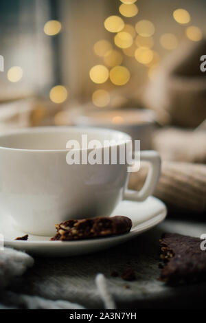 Cup of coffe with milk and chocolate cookies on warm wool blanket, cozy winter home Stock Photo