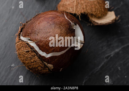 Cracked coconut on dark stone background. Exotic food concept. Stock Photo