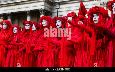 Members of Red Brigade from Extinction Rebellion movement in their costumes protesting on the steps of Trafalgar Square during the third day of their two weeks action in Westminster. The climate change activists are calling for the UK Government to take urgent action on climate change. Stock Photo