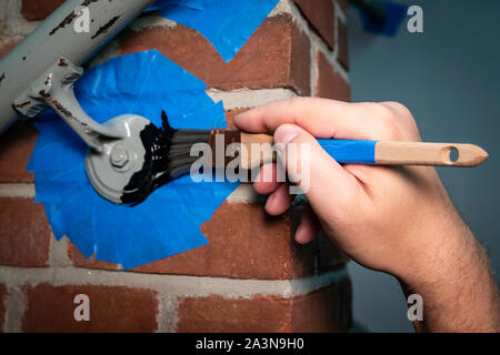 Hand painting metal hand railing on brick wall - prepped with painter's tape Stock Photo