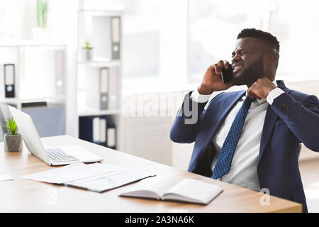 Stressed young manager talking by phone with colleagues Stock Photo