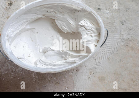 Mixed putty solution in a pail ready to be used. Construction works concept. Copy space Stock Photo