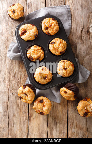 Mediterranean muffins with sun-dried tomatoes and cheddar cheese close-up in a baking dish on the table. Vertical top view from above Stock Photo