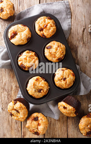 Snack savory muffins with sun-dried tomatoes and cheddar cheese close-up in a baking dish on the table. Vertical top view from above Stock Photo