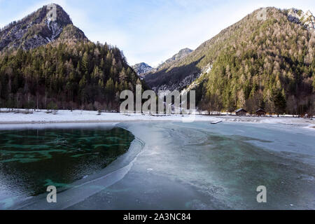 Beautiful view at sunset of the peaceful lake Fucine Tarvisio, Italy with green forest and snowy mountains in the background . Stock Photo