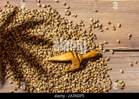 Wooden scoop with hemp seeds and marijuana leaf shadow on wooden table Stock Photo