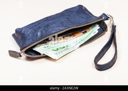 open blue leather wristlet purse bag with credit cards and euro banknotes on pale brown table Stock Photo