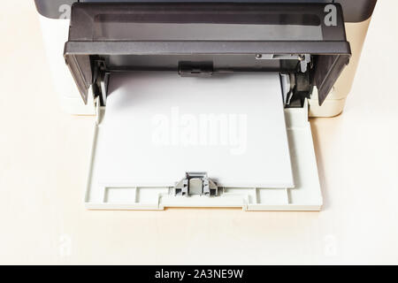 stack of white paper sheets in printer tray of multi function device on table in office Stock Photo