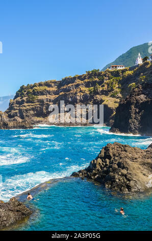 Seixal, Madeira, Portugal - Sep 13, 2019: Couple swimming in a natural swimming pool in the Atlantic ocean. Pools made up of volcanic rock, into which the sea flows naturally. Tourist attractions. Stock Photo