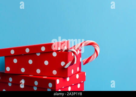Red gift boxes with white spots and candy canes, on a blue background. Christmas presents. Xmas red gifts. Gifting concept. Winter holiday tradition. Stock Photo