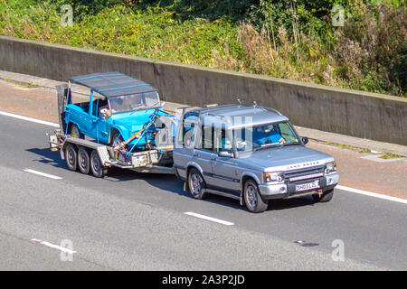 2003 Land Rover Discovery TD5 S, Land rover, towing 1960s sixties Austin Morris Mini Moke restoration project, rare barn garage find on car trailer; UK Vehicular traffic, transport, classic British cars, south-bound on the 3 lane M6 motorway highway. Stock Photo