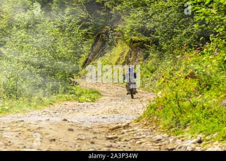 Ukraine, Carpathians. Biker rides on a dirt mountain road Stock Photo