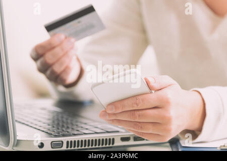 Womans hand holding credit card and smartphone over notebook, concept of e-commers and mobile payment Stock Photo
