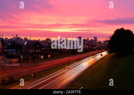 A pink sunrise over Leeds City Centre viewed from Armley Road. Stock Photo