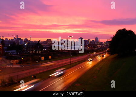 A pink sunrise over Leeds City Centre viewed from Armley Road. Stock Photo