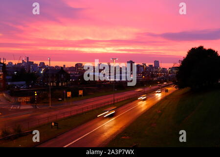 A pink sunrise over Leeds City Centre viewed from Armley Road. Stock Photo