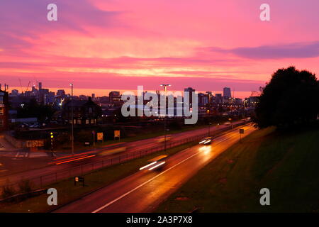 A pink sunrise over Leeds City Centre viewed from Armley Road. Stock Photo