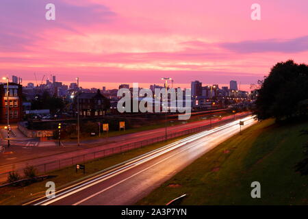 A pink sunrise over Leeds City Centre viewed from Armley Road. Stock Photo