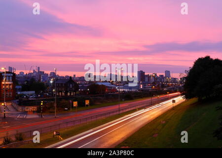 A pink sunrise over Leeds City Centre viewed from Armley Road. Stock Photo