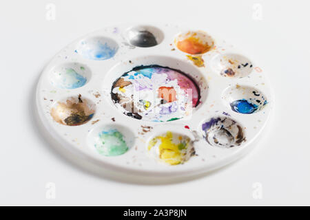 Artist palette full of dried coloured paint, isolated on a white background with a shallow depth of field Stock Photo