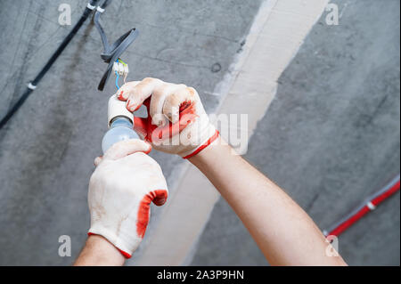 An electrician is setting a light bulb for temporary lighting. Stock Photo