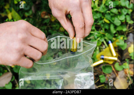 The man's hand is putting the used batteries into the bag. Stock Photo