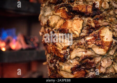 Charcoal shawarma meat. Closeup of chicken meat collected on a vertical skewer and grilled on charcoal Stock Photo