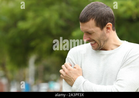 Man suffering itching cratching arm standing in a park Stock Photo