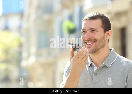 Happy man using voice recognition on mobile phone to send a recorded message in the street Stock Photo