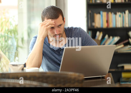 Worried adult man checking laptop online content sitting in a coffee shop Stock Photo