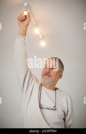 Senior man installing a ceiling light n a freshly renovated appartment Stock Photo