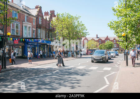 Cars waiting whilst two young ladies walk across the road on a Zebra Crossing on a sunny day in Lytham Lancashire England UK Stock Photo