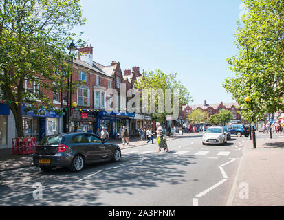 Cars waiting whilst a senior couple walk across the road on a Zebra Crossing on a sunny day in Lytham Lancashire England UK Stock Photo