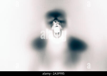 Inversed  color version of Creepy man screaming behind the frosted glass. Stock Photo