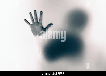 Inversed  color version of Creepy man holding the frosted glass with one hand. Stock Photo