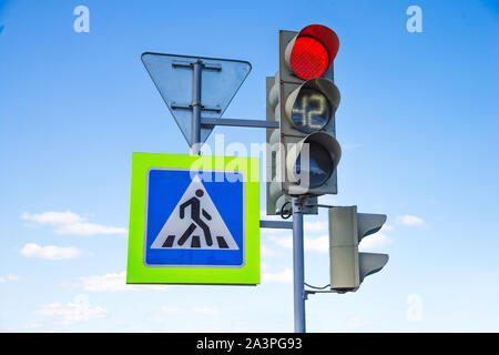 Red light traffic light signal with readout of remaining time and crosswalk road sign with sky reflection  on the blue sky background Stock Photo