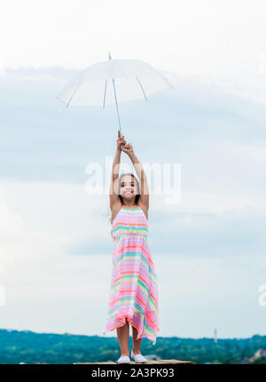 Fairy tale character. Feeling light. Girl with light umbrella. Anti gravitation. Fly drop parachute. Dreaming about first flight. Kid pretending fly. Happy childhood. I believe i can fly. Touch sky. Stock Photo
