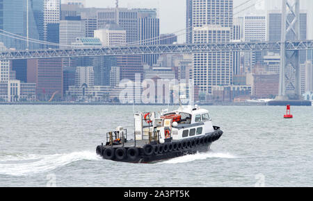 Oakland, CA - February 08, 2019: Tugboats are powerful for their size and strongly built. Tugboat in the San Francisco Bay with city in the background Stock Photo