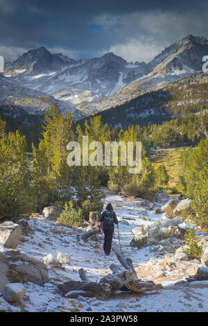 woman hiking in the snow covered trail along Little Lakes Valley in the Eastern Sierra Nevada Mountains. California USA Stock Photo